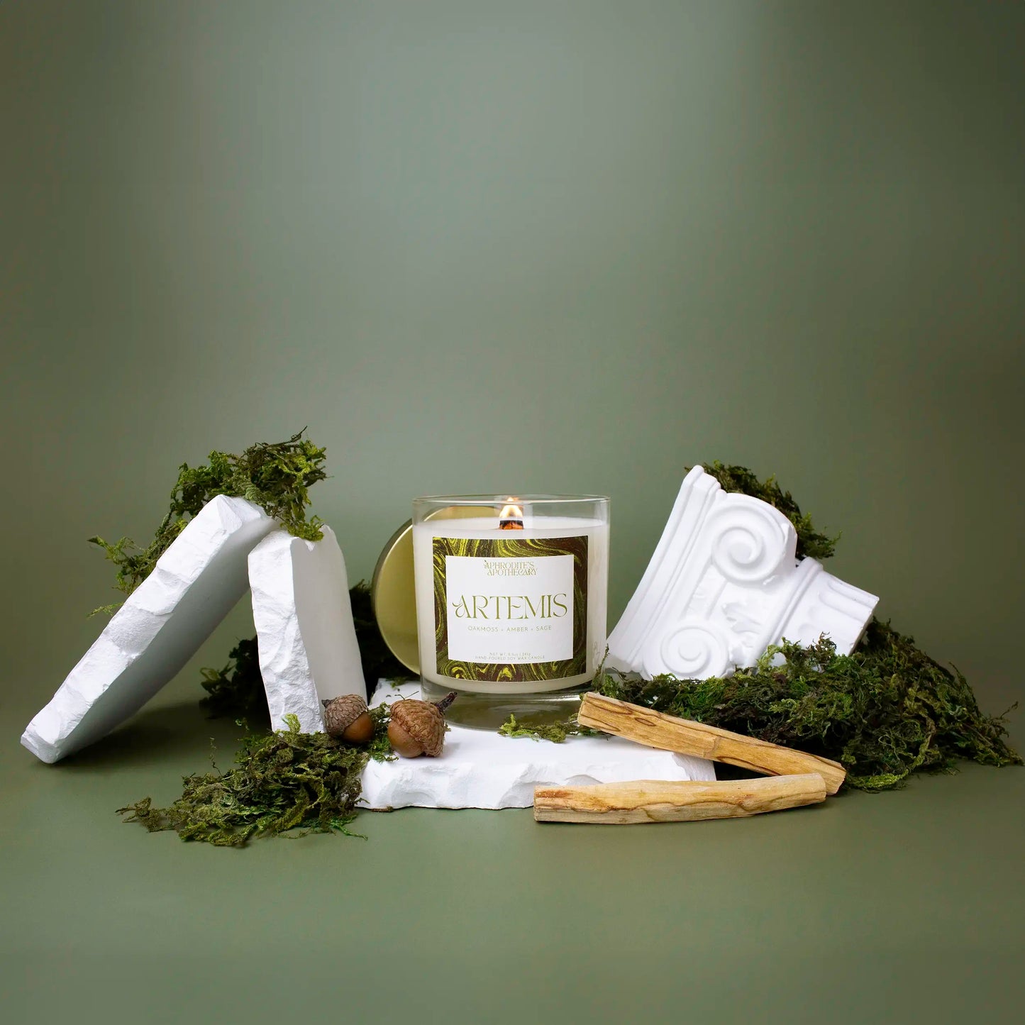Artemis Candle 8.5 oz on a Greek themed photo set covered in moss