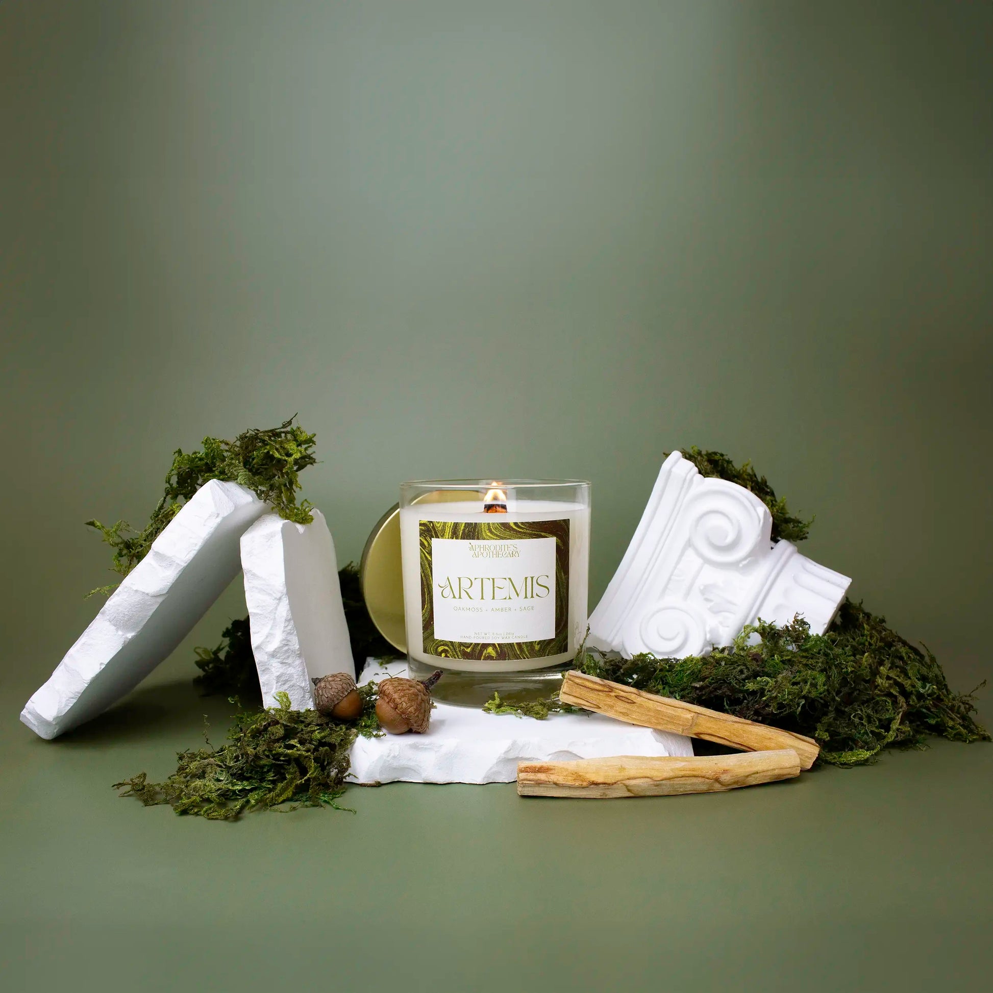 Artemis Candle 8.5 oz on a Greek themed photo set covered in moss