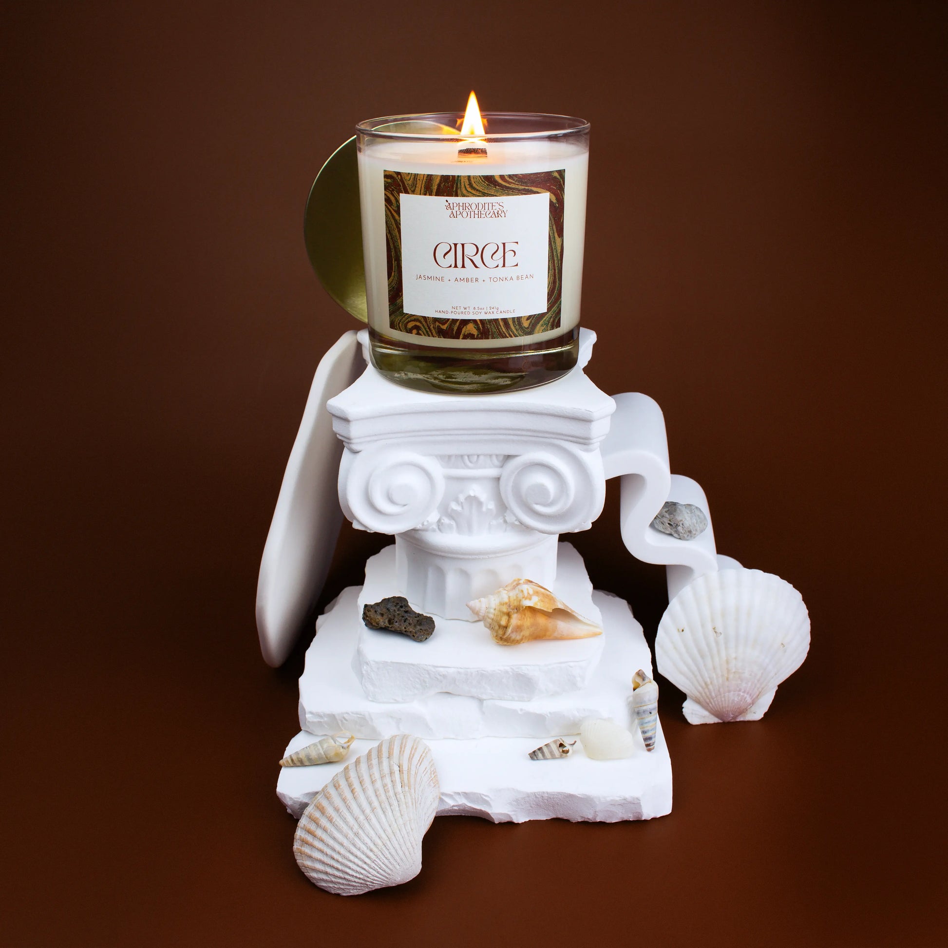 Circe Candle 8.5 oz on Greek themed photo set with jasmine flowers, seashells, and beach rocks