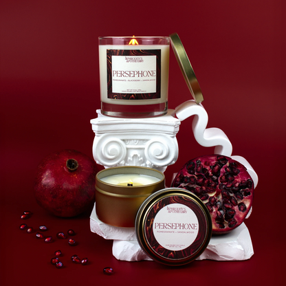 Persephone Candle 8.5 oz and Persephone Candle 4 oz on a Greek themed photo set with pomegranates and pomegranate seeds, deep red background.